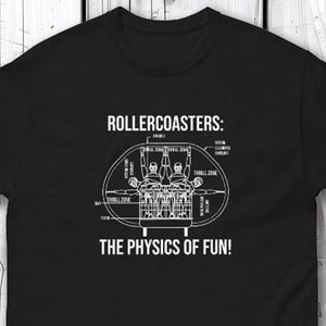 May include: Black t-shirt featuring a white diagram of a roller coaster with the text "ROLLERCOASTERS: THE PHYSICS OF FUN!". The diagram includes labels and a depiction of passengers in the car.