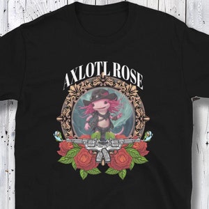 Könnte beinhalten: Schwarzes T-Shirt mit einem Aufdruck eines Axolotls, der einen Cowboyhut trägt und ein Paar Pistolen hält. Der Axolotl befindet sich in einem goldenen Rahmen mit dem Text "AXOLOTL ROSE" darüber.