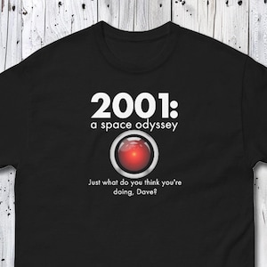 Puede incluir: Camiseta negra con el texto "2001: a space odyssey" y un círculo rojo. La cita "Just what do you think you're doing, Dave?" está impresa debajo.
