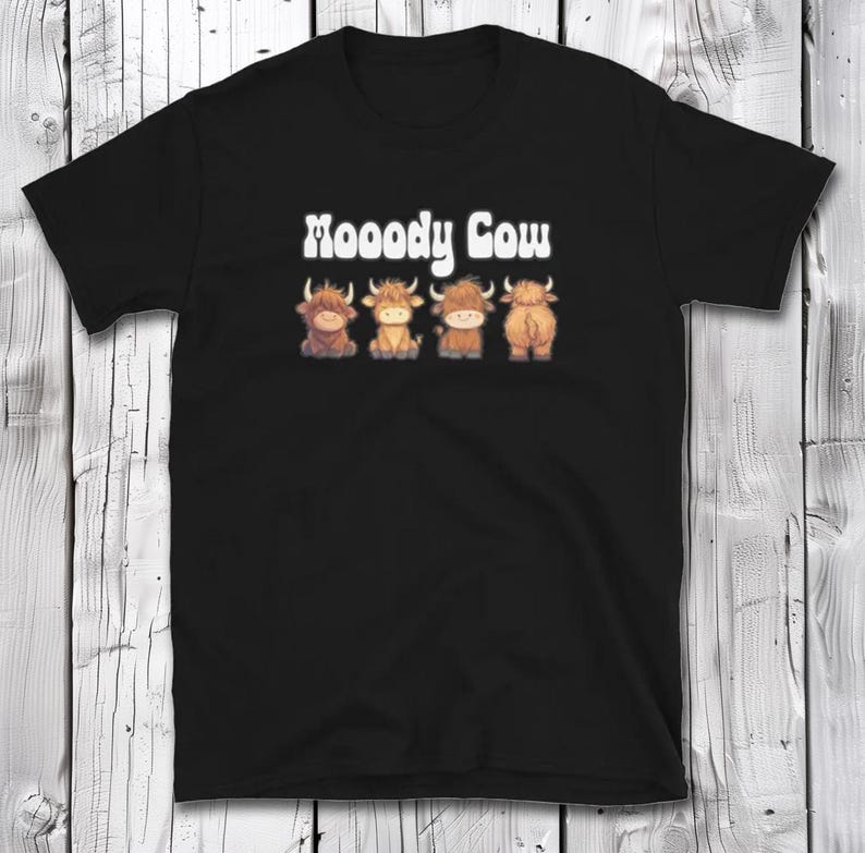 May include: Black t-shirt with the text "Moody Cow" in white letters. Four cartoon cows are lined up below the text.