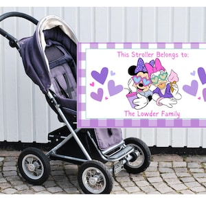 Op de afbeelding: Een paarse kinderwagen met een bordje met de tekst "This stroller belongs to: The Lowder Family." Op het bord staan Minnie Mouse en Daisy Duck met zonnebrillen en ijs. Paarse harten versieren het bord.