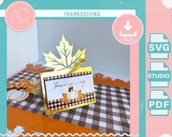 May include: Thanksgiving-themed digital design with a gold maple leaf and a card that says "Thanksgiving" with a pumpkin illustration. The background features a black and white checkered pattern and orange accents. Includes SVG, Studio, and PDF file options.