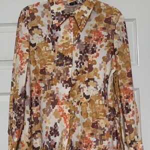 May include: A long-sleeved button-up shirt with a white background and a brown, orange, and purple abstract print.