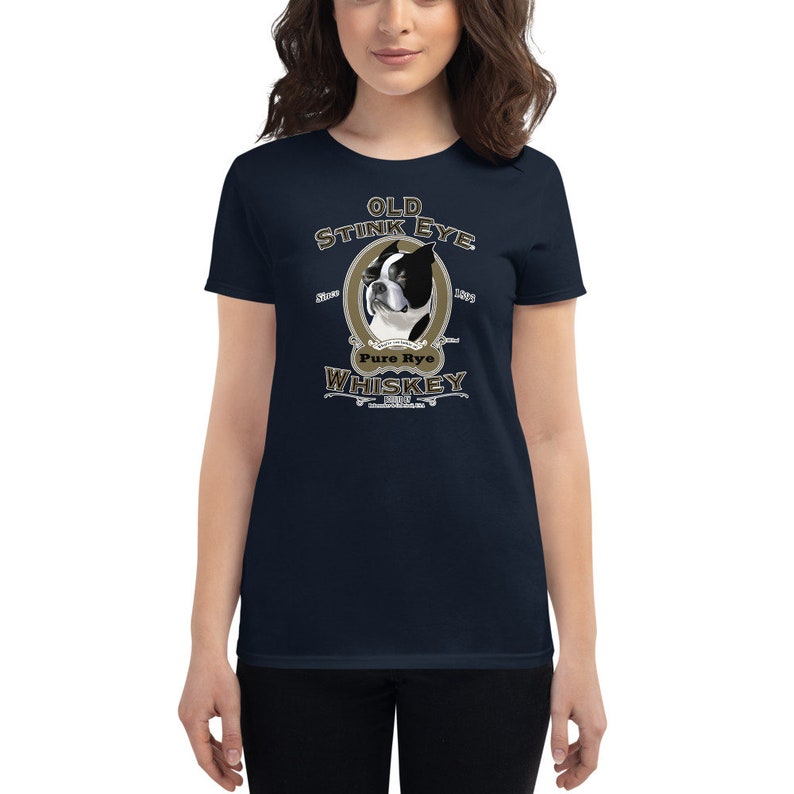 May include: A navy blue women's t-shirt with a graphic of a Boston Terrier dog with the text "Old Stink Eye Pure Rye Whiskey" in a gold and brown vintage style.
