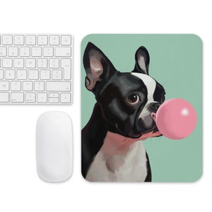 May include: A black and white French bulldog with a pink bubble gum in its mouth. The dog is looking to the right and has a playful expression. The background is a light blue-green color.