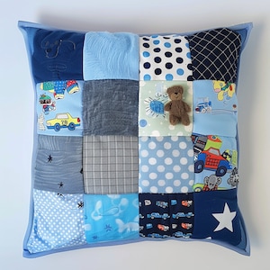 May include: A blue patchwork pillow with a variety of patterns, including stars, polka dots, and cars. A small teddy bear is sewn onto the pillow.