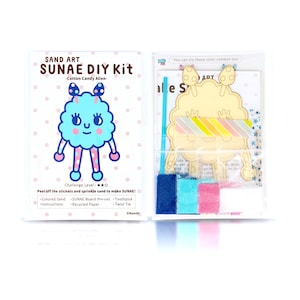 May include: A craft kit for making a sand art picture of a blue and pink cartoon character called "SUNAE". The kit includes coloured sand, a pre-cut wooden board, a toothpick, and a twist tie. The instructions are included on the packaging.