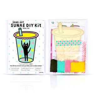 May include: A DIY sand art kit featuring a boba tea cup with a black cat inside. The kit includes coloured sand, a pre-cut board, a toothpick, and a twist tie. The packaging is pink, yellow, and blue with the words "SAND ART SUNAE DIY Kit -Boba Cat- Challenge Level: ★★ Peel off the stickers and sprinkle sand to make SUNAE! Coloured Sand SUNAE Board (Pre-cut) Toothpick Twist Tie ©Nasshi" printed on it.