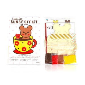 May include: A sand art DIY kit featuring a bear in a cup of coffee. The kit includes coloured sand, a pre-cut board, a toothpick, and a twist tie. The challenge level is rated with three stars.
