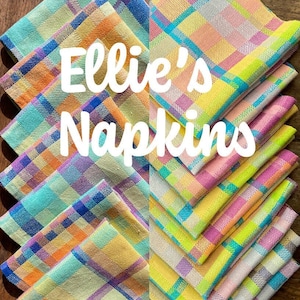 Może przedstawiać: Stosik kolorowych serwetek w kratę z napisem "Ellie's Napkins" w białym kolorze.