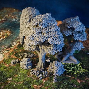 Op de afbeelding: Een verzameling grijze miniatuurbomen en -struiken, waarschijnlijk voor tabletop-spellen of modelscènes. De bomen hebben gedetailleerde bladtexturen en de scène is geplaatst op een groene en bruine terreinmat.
