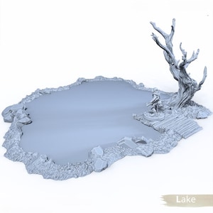 Op de afbeelding: Een grijs miniatuurmeermodel met een rotsachtige kustlijn, een kleine houten steiger en een gedetailleerde boom. Een klein figuur staat op de steiger. Het woord "Lake" staat onderaan afgedrukt.