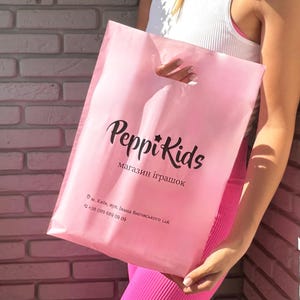 ブティック向けピンクのカスタムロゴショッピングバッグ、カスタムロゴプラスチックギフトバッグ、ビジネス向けロゴショッピングバッグ、ギフトバッグ、カスタムトートバッグ