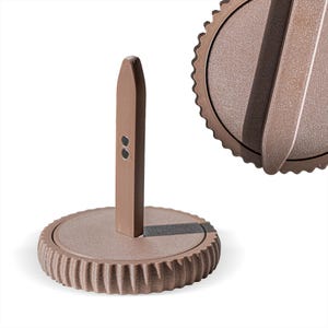 Può includere: Un portarotolo marrone con una base rotonda e strutturata e un palo verticale. Il supporto ha un design semplice e moderno ed è realizzato in un materiale opaco dai toni neutri. La base ha un bordo scanalato.