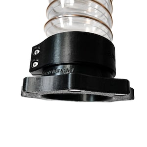 Może przedstawiać: Przezroczysty, elastyczny wąż z czarnym złączem i kołnierzem. Wąż ma spiralny wzór z miedzianym wzmocnieniem. Złącze ma dwie śruby i tekst. Kołnierz jest prostokątny z zaokrąglonymi narożnikami.