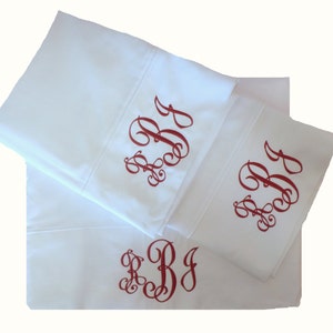May include: Three white pillowcases with red embroidered initials "RBJ" in a cursive font.