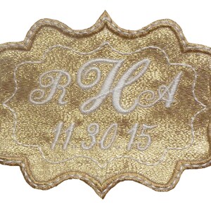 May include: Gold-colored fabric patch with a white embroidered design. The design includes the initials "R & H" and the date "11.30.15".