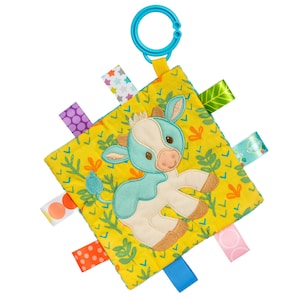 May include: A yellow, blue, and white baby security blanket with a blue and white cow applique and colorful fabric tags. The blanket has a blue plastic ring for attaching to a stroller or car seat.