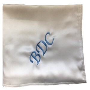 May include: White satin fabric with the letters "BDC" embroidered in light blue.