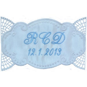 May include: White embroidered fabric with a blue embroidered design. The design includes the initials "R.C.D." and the date "12.1.2013".