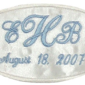May include: White oval satin patch with blue embroidered initials "E H B" and the date "August 18, 2007".