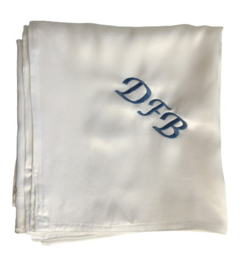May include: White satin fabric with the initials "DFB" embroidered in blue.