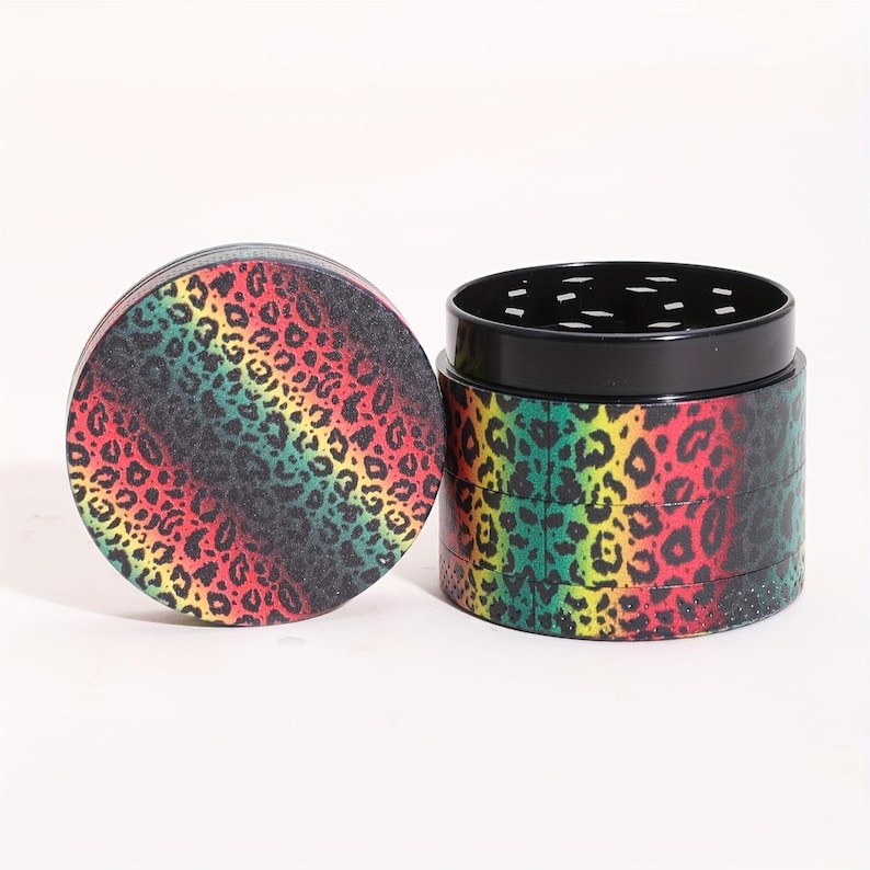 Op de afbeelding: Een meerlaags grinder met een zwarte metalen basis en een kleurrijk luipaardprintontwerp. De grinder heeft een rood, geel, groen en zwart kleurenschema.