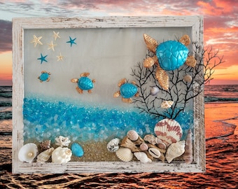 May include: A framed artwork featuring a beach scene with turquoise sea turtles, seashells, and blue glass beads. The background is a sunset sky with clouds.