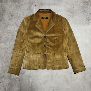 Puede incluir: Una blazer de ante marrón con un diseño clásico. La chaqueta presenta un cuello con solapas, dos bolsillos delanteros y tres botones marrones. La blazer tiene un corte entallado y un aspecto suave y texturizado.