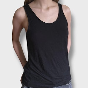 May include: A black tank top with a scoop neckline. The top is made of a soft, lightweight fabric. The tank top is paired with gray denim jeans.