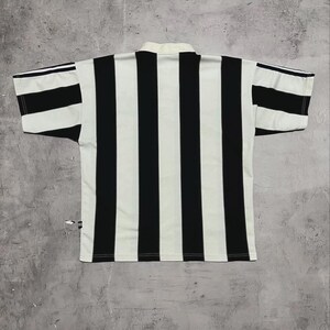 Puede incluir: Camiseta de manga corta a rayas blancas y negras. La camiseta tiene cuello blanco y rayas negras verticales en la parte delantera y trasera. Las mangas tambi&eacute;n tienen rayas blancas y negras. La camiseta es de material ligero.