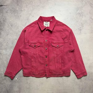 May include: A red denim jacket with a button-up front, two chest pockets, and two side pockets. The jacket has a classic collar and a label on the back of the neck. The jacket is a medium weight and is likely made of cotton.