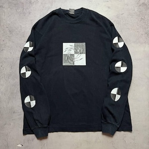 May include: A black long-sleeve shirt featuring a central square graphic with a swirling white design on a checkered background and the text UP EVIL. Each sleeve displays three circular black and white crash test dummy patterns.