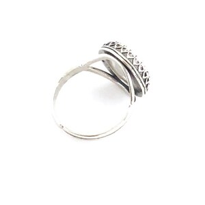 Pu&ograve; includere: Un anello d'argento con una pietra ovale di colore chiaro. L'anello presenta una fascia decorativa attorno alla pietra e una fascia semplice ed elegante. L'anello &egrave; posto su uno sfondo bianco, evidenziando il suo design e la sua maestria.