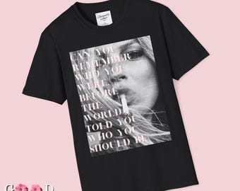 May include: Black t-shirt featuring a monochrome image of a woman smoking. Pink text overlay reads: "CAN YOU REMEMBER WHO YOU WERE BEFORE THE WORLD TOLD YOU WHO YOU SHOULD BE."