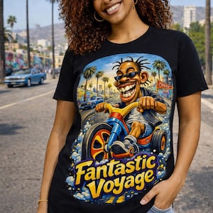 May include: Black t-shirt featuring a cartoon illustration of a man riding a tricycle with the text "Fantastic Voyage". The graphic is set against a backdrop of palm trees and a blue sky.