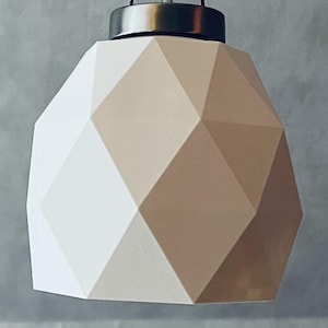 May include: Geometric pendant light with a faceted, off-white shade and a brushed metal cap. The shade's design features a series of angled planes, creating a modern, architectural aesthetic. The light fixture is suspended from a black cord.