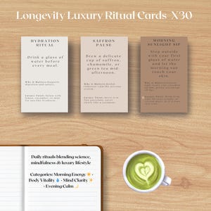 Może przedstawiać: Kompozycja o tematyce wellness z kartami rytuałów, notatnikiem i filiżanką zielonej herbaty. Karty z tekstem dotyczą "Hydration Ritual", "Saffron Pause" i "Morning Sunlight Sip". Notatnik zawiera codzienne rytuały.