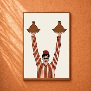 May include: A framed wall art print featuring a cartoon illustration of a person wearing a red fez and sunglasses, dressed in a brown and white striped shirt, holding two brown conical tajine cooking pots high above their head.