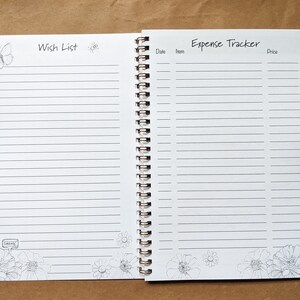 Pode incluir: Um caderno branco de espiral com uma se&ccedil;&atilde;o de lista de desejos e um rastreador de despesas. O caderno tem um design de borboleta e flores.