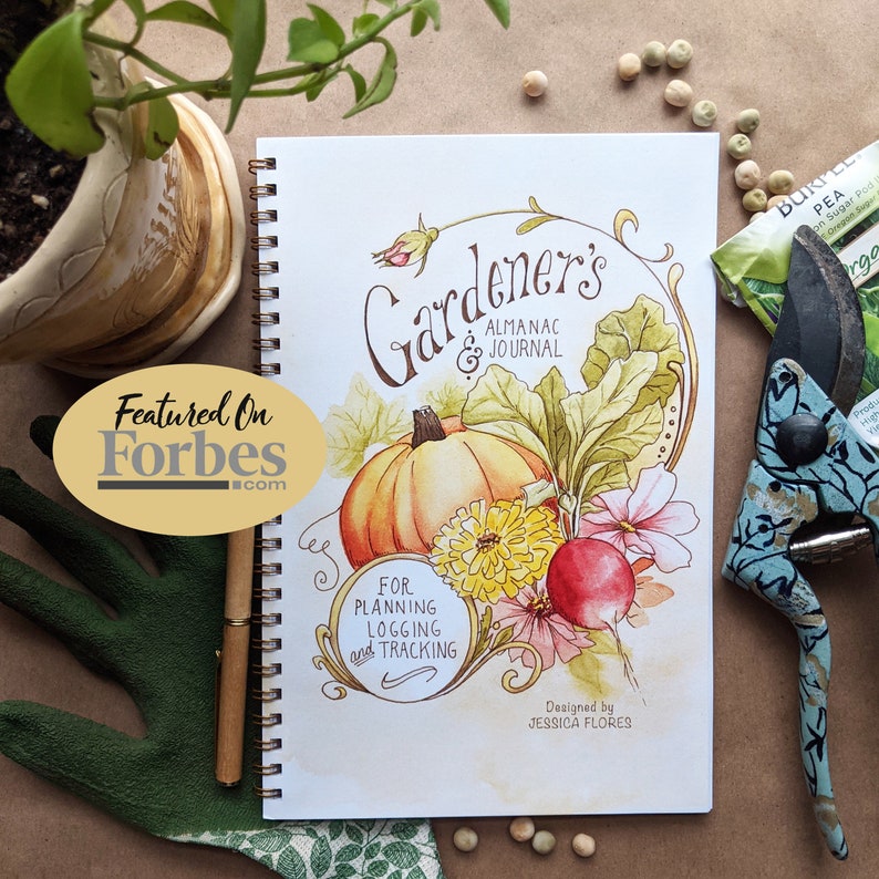 Pode incluir: Um di&aacute;rio branco com uma ilustra&ccedil;&atilde;o de aquarela de uma ab&oacute;bora, um rabanete e flores. O di&aacute;rio &eacute; intitulado "Gardener's Almanac & Journal" e diz "For Planning, Logging and Tracking". O di&aacute;rio foi desenhado por Jessica Flores.