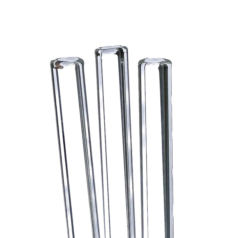 Three clear glass straws are arranged in a row against a white background.