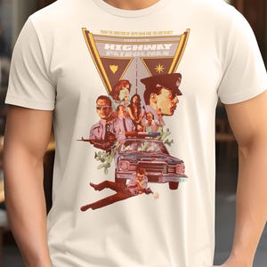 May include: A white t-shirt with a vintage-style graphic of the movie "Highway Patrolman". The graphic features a police car, a group of people, and the movie title in a bold font.