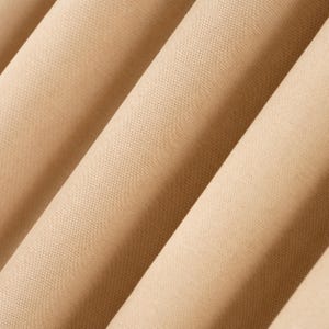 Könnte beinhalten: Nahaufnahme von gefaltetem beigem Stoff. Der Stoff hat eine subtile Textur und ist in diagonalen Falten angeordnet, wodurch ein Gefühl von Tiefe und Dimension entsteht. Die Farbe ist ein warmer, neutraler Ton, der für verschiedene Anwendungen geeignet ist.