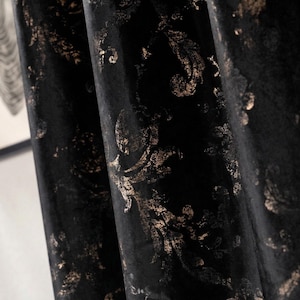 May include: Close-up of black velvet curtains with a gold floral pattern. The fabric is draped in soft folds, creating shadows and highlights. The gold design adds a touch of elegance to the dark background, suitable for home decor.