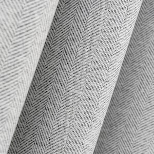 Puede incluir: Primer plano de una tela enrollada con un patrón de espiga gris y blanco. La tela tiene una apariencia texturizada, con el tejido diagonal creando una textura visual. La paleta de colores es neutra, con tonos de gris y blanco.