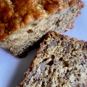 May include: Close-up of a banana bread loaf, sliced open to reveal the moist, dense crumb and visible banana chunks.