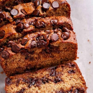 May include: Close-up of a loaf of banana bread with chocolate chips. The bread is sliced and shows the inside with chocolate chips throughout.