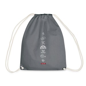 Pode incluir: Mochila cinza com cordão com símbolos tribais brancos impressos verticalmente. A bolsa tem cordões brancos e uma pequena etiqueta vermelha com texto branco. Os símbolos incluem espirais, sóis e outras formas geométricas.