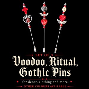 May include: Set of three gothic pins with red and silver accents. Each pin features unique designs, including a cross, a heart with wings, and a skull. The pins are displayed against a black background, with text that reads "Voodoo, Ritual, Gothic Pins."